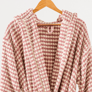 Närbild på rosa morgonrock i bomull – pom pom-struktur och mjuk yta