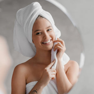Kvinna med vit ansiktshandduk efter dusch - mjuk bomullshandduk 30x30cm spa hemma
