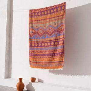 Orange-lila etnisk hammamhandduk med geometriskt mönster hängande på vit vägg - lifestyle