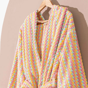 Flerfärgad randig morgonrock med pompomstruktur hängande på trägalge