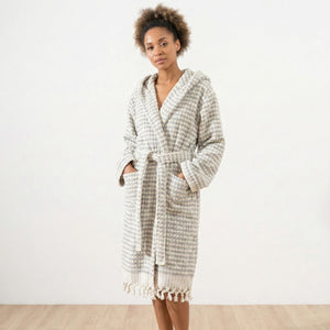 Kvinna i grå rutmönstrad morgonrock med pompomstruktur och fransar