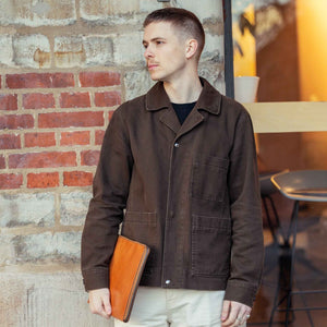 Person som står och håller ett brunt laptopfodral Grimmared i handen