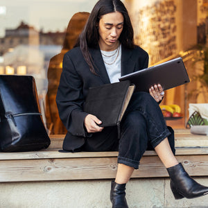Person som tar ut en laptop ur ett svart Grimmared laptopfodral på ett café