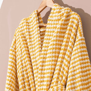 Gul randig morgonrock med pompomstruktur hängande bakifrån på trägalge