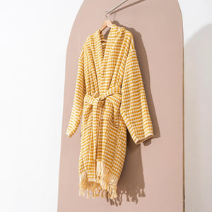 Gul randig morgonrock med pompomstruktur och fransar hängande på trägalge