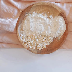 Ekologiskt kokosmjölk badsalt ingredienser i träskål med havre och mineralsalt.