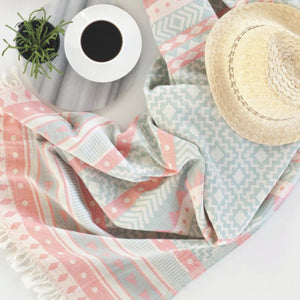 Lovely hamamhandduk i rosa och ljusblå med medelhavsmönster, flatlay med kaffe och halmhatt, sommarvibes