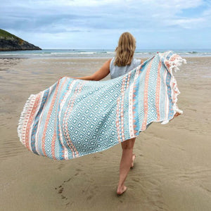 Lovely hamamhandduk på strand med modell, medelhavsinspirerad design i blått och aprikos