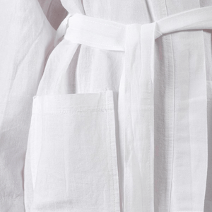 Närbild på Serenity morgonrockens ficka och skärp i vitt linne, mjuk och naturlig linnетextur