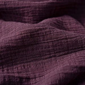 Närbild på muslin sängöverkast Wine i djup vinröd färg, handvävt ekologisk bomull, mjuk och luftig textur