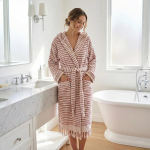 Kvinna i rosa rutmönstrad morgonrock med pompomstruktur i ljust badrum