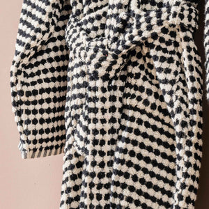 Svart-vit morgonrock med pompomstruktur - närbild på fickor och rutmönster