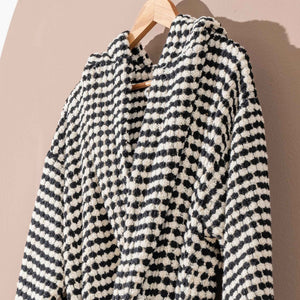 Svart-vit morgonrock med pompomstruktur hängande - närbild på krage och rutmönster