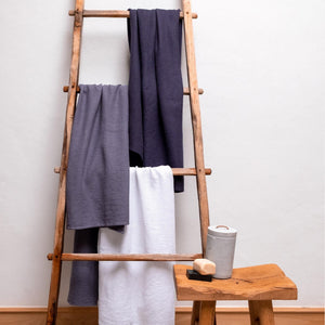 Våfflat badlakan i ekologisk bomull i mörkgrå, vitt och mörkblå hängda på trästege, GOTS-certifierad